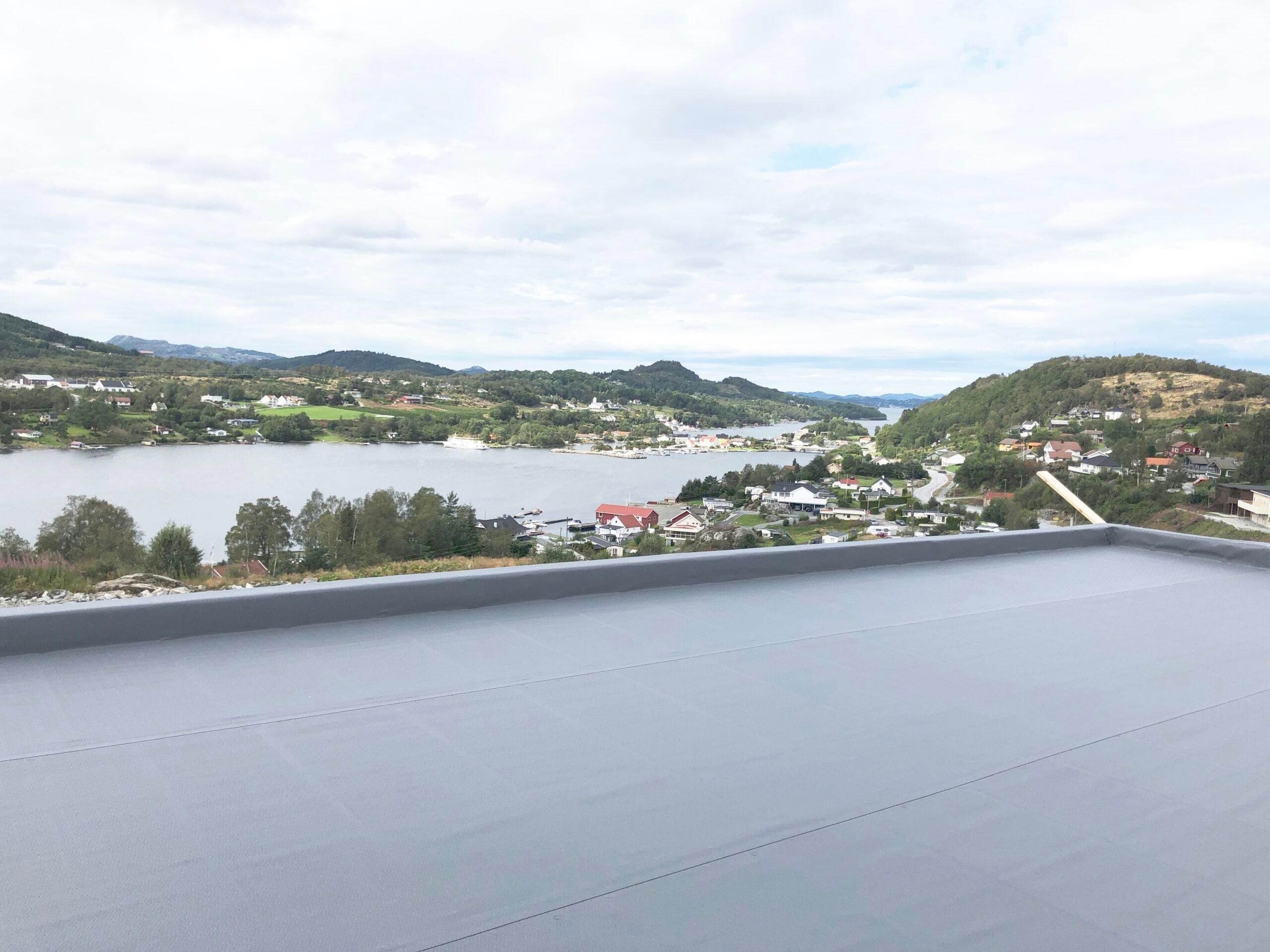 A flat membrane roof with a view over a fjord