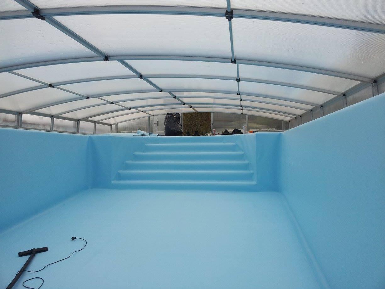 A pool lined with light blue membrane under a clear cover