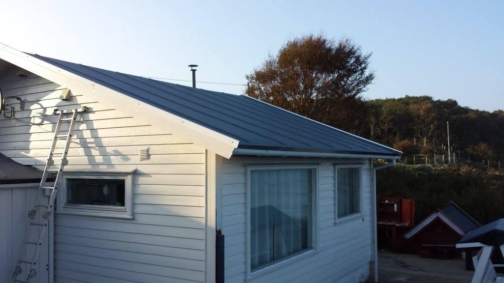 A white house with a dark profiled metal roof